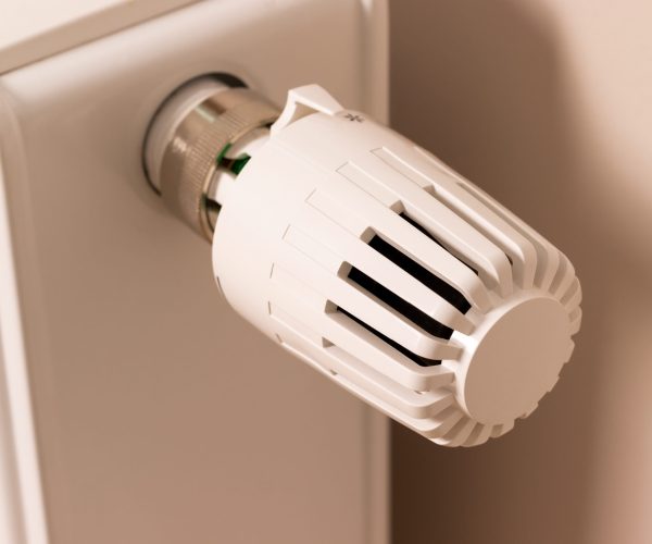 Control valve of home heating radiator in modern living room. Temperature regulator. Low temperature reduces heating costs
